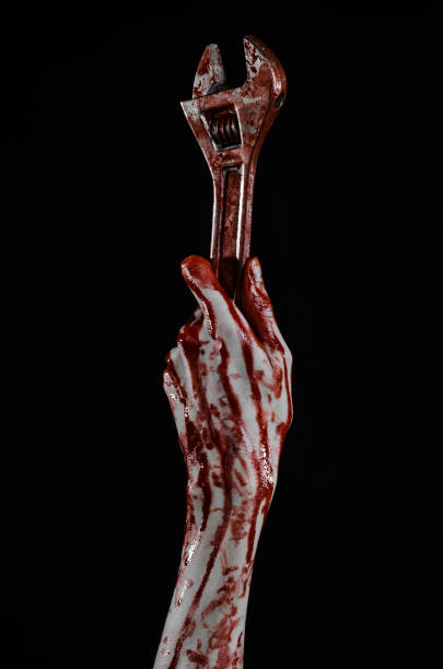 istock Halloween theme: bloody hand holding a big wrench on a black background 916817532