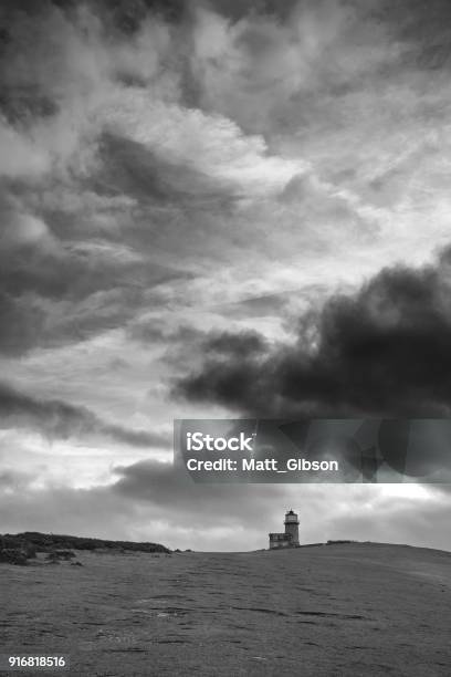 Stunning Black And White Landscape Image Of Belle Tout Lighthouse On South Downs National Park During Stormy Sky Stock Photo - Download Image Now