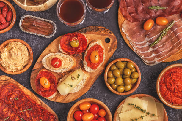 istock Typical spanish tapas concept. Concept include slices jamon, chorizo, sausage, bowls with olives, tomatoes, anchovies,  mashed chickpeas, cheese. 916836426