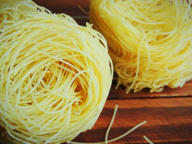 istock Raw pasta, macaroni nests on dark wooden background. 916840300