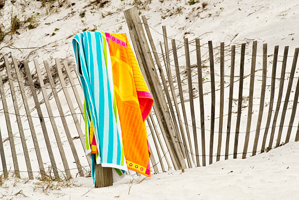 orange und blue beach towel hängen über einen verwitterten Zaun – Foto