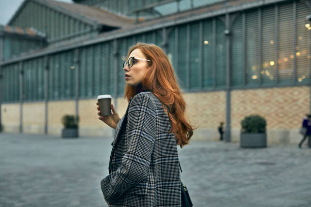 Woman looking away while having coffee in city