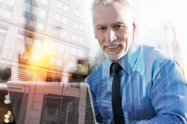istock Positive mature man smiling while sitting with a laptop 916855890