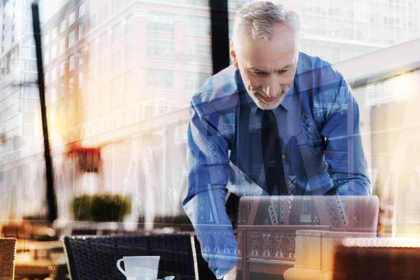 istock Smiling man leaning to his laptop while being in a cafe 916858794