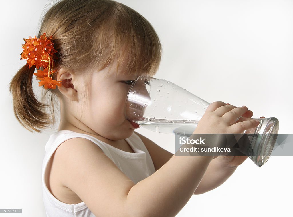 A small child drinking out of a pint glass The small girl is drincking water from glas. Drinking Stock Photo