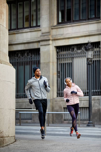 istock Confident man and woman jogging against building 916859474