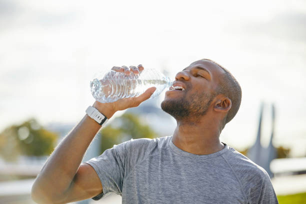 istock Tired man drinking water from bottle on sunny day 916859532