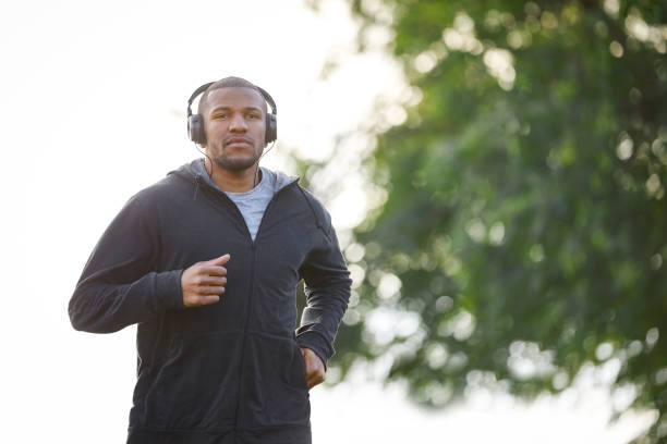 istock Young man jogging while listening music at park 916859564