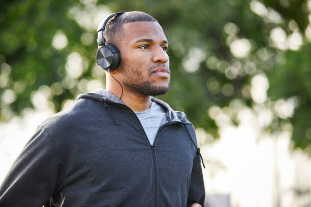 istock Thoughtful man wearing headphones at park 916859570
