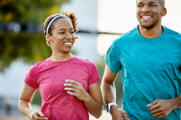 istock Smiling couple looking away while jogging in park 916859642