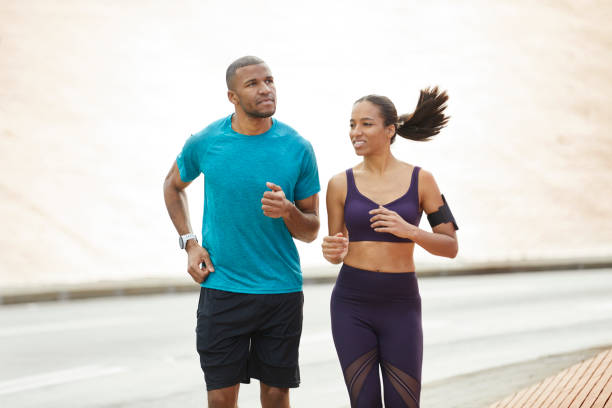 istock Determined couple jogging together on city street 916859778
