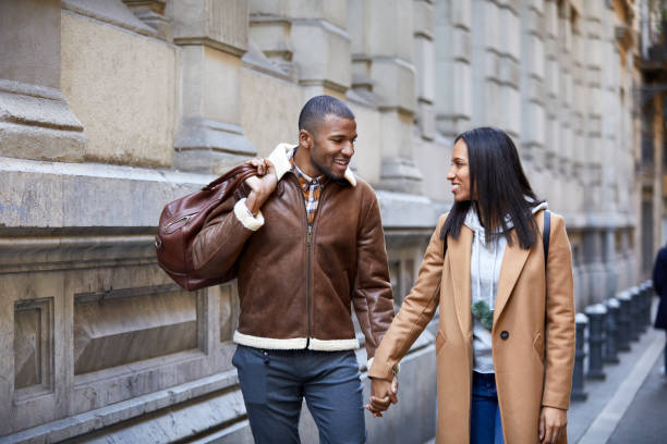istock Smiling couple holding hands while walking in city 916862192