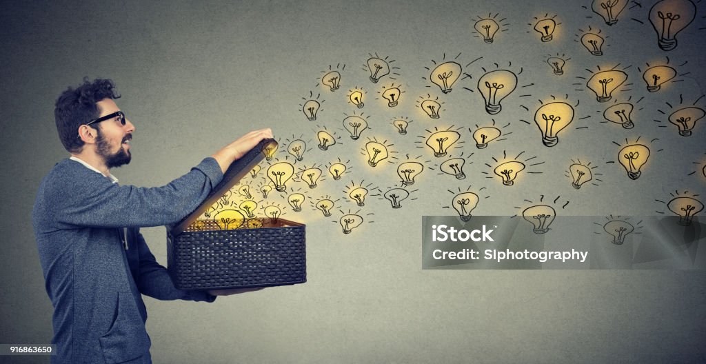 Side view of a man holding box with brilliant ideas being creative Side view of young man holding box with brilliant ideas Inspiration Stock Photo