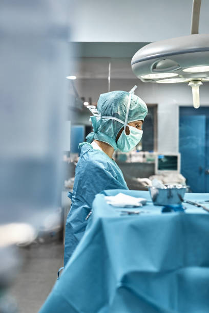 Veterinarian performing surgery in hospital Side view of veterinarian performing surgery in hospital. Male doctor is wearing protective workwear. Surgeon is in operating room. surgical light stock pictures, royalty-free photos & images