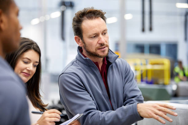 istock Engineer discussing with manager in car factory 916867884