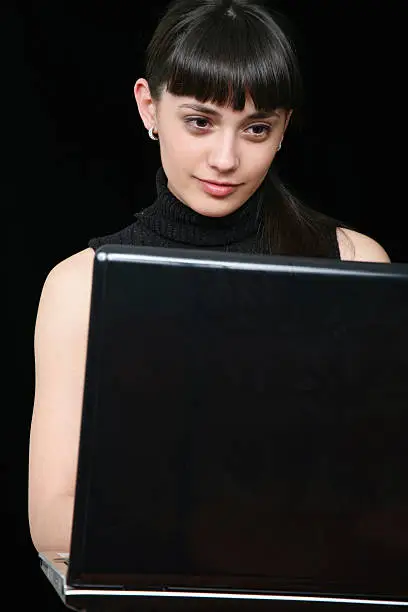 Beautiful young girl writing on the laptop