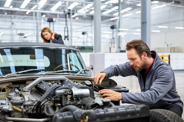 Photo of Male engineer repairing vintage car in industry