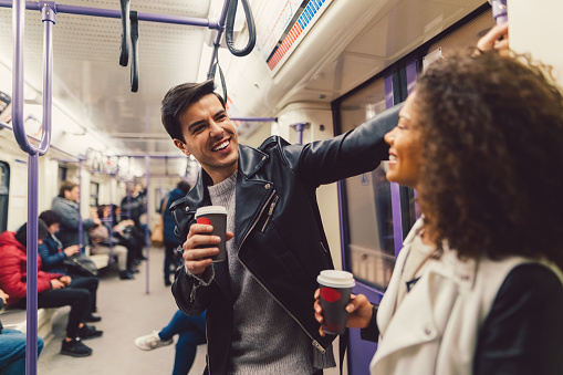 Young people talking and drinking coffee while travelling in the subway