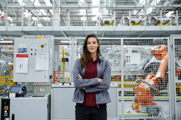istock Confident female engineer standing at car plant 916875550