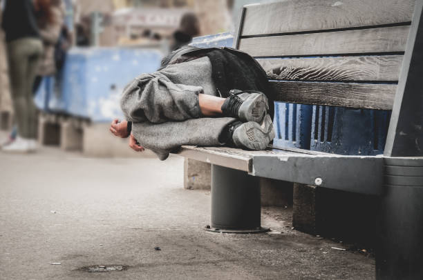 pobre hombre sin hogar o refugiados durmiendo en el banco de madera en la calle urbano de la ciudad, concepto de documental social, enfoque selectivo - vagabundo fotografías e imágenes de stock