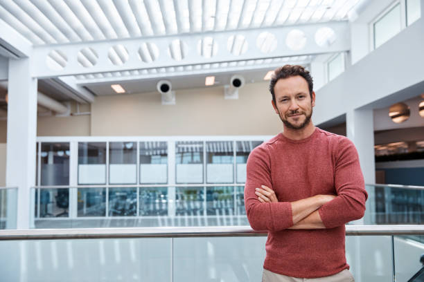 istock Businessman standing arms crossed at railing 916890498