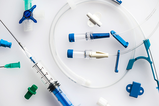 Neatly arranged syringe with needle and plastic tubes for central venous catheter insertion on a white background