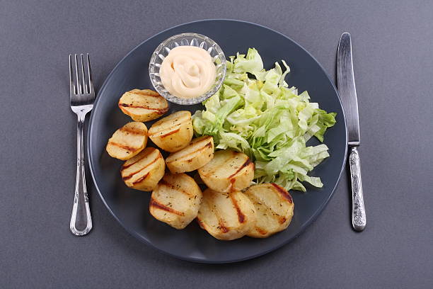 Roasted potatoes slices with chopped salad and sauce stock photo