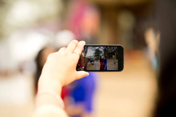 Woman taking photos of friends using mobile camera at Indian Fair