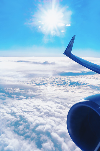 Berlin, Germany - December 14, 2017: Wing of Ryanair aircraft and horizon with blue sky and clouds.