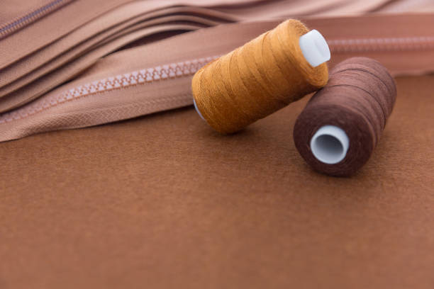 istock Spools of thread and zippers on brown background 916919140