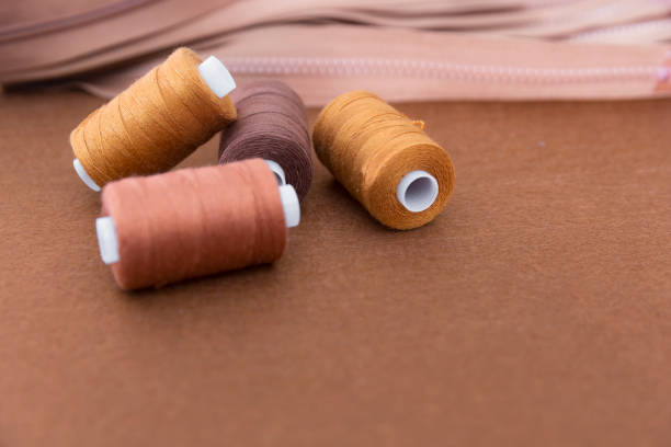 istock Spools of thread and zippers on brown background 916919144