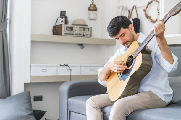 istock Handsome man playing guitar in the living room. 916925466