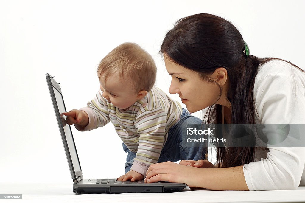 Mother looking at laptop as toddler points to screen happy family with laptop Adult Stock Photo