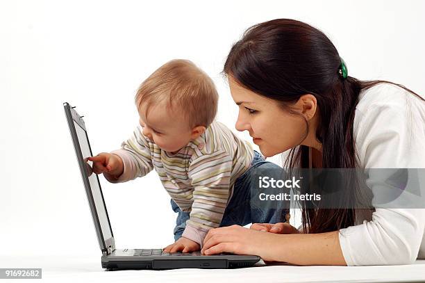 Mother Looking At Laptop As Toddler Points To Screen Stock Photo - Download Image Now