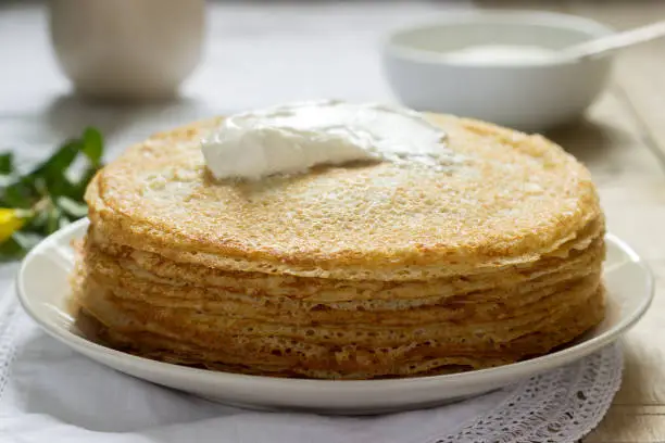 Delicate fishnet pancakes with sour cream. Selective focus.