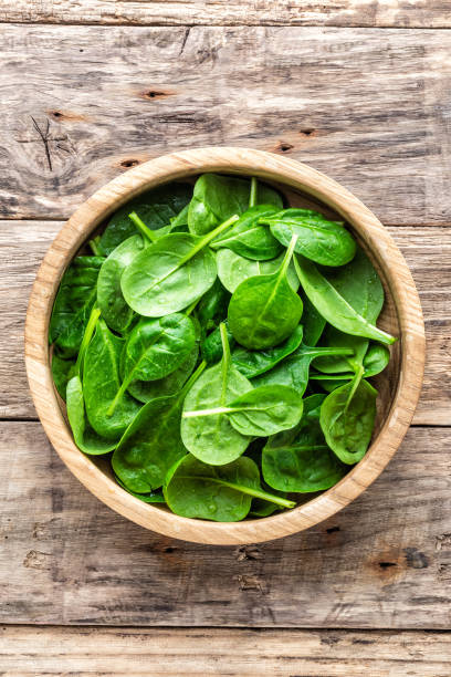 新鮮なベビーほうれん草の木製の背景にボウルの葉します。 - organic spinach leaf vegetable vegetable ストックフォトと画像