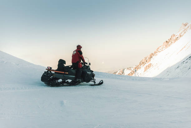 istock Man lifeguard snowmobile rides in the mountains. 916931172