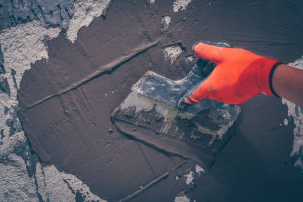 istock The worker aligns the wall with a tile adhesive applying it with a spatula, preparation for tiling 916931698