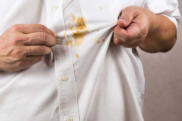 istock Person pointing to spilled curry stain on white shirt. 916932156