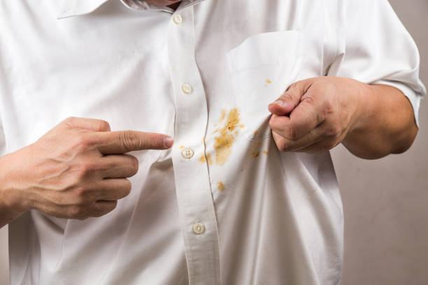 person pointing to spilled curry stain on white shirt. - stained imagens e fotografias de stock