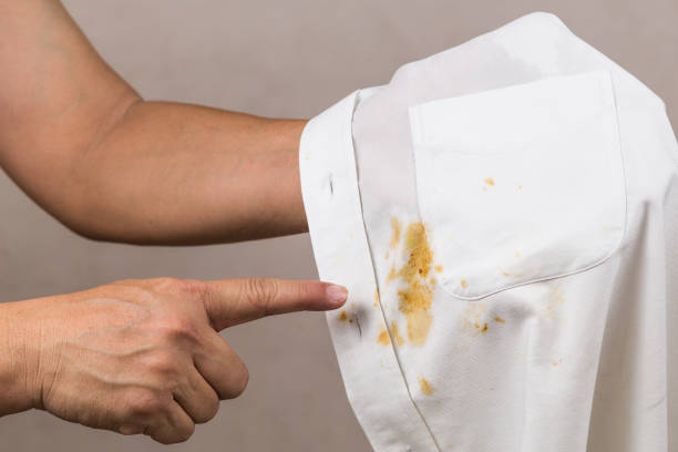 istock Person pointing to spilled curry stain on white shirt. 916932338