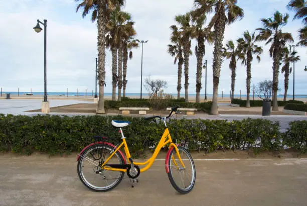 Photo of A bicycle parked in the seafront of the popular La Malvarrosa beach, in Valencia, Spain.