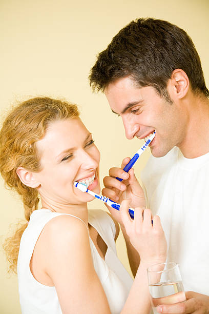 Casal Jovem limpeza dentes juntos na casa de banho - fotografia de stock