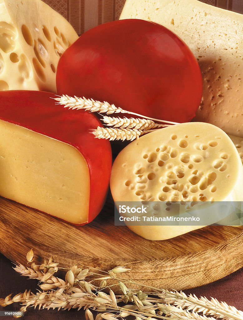 A different selection of cheeses on a wooden board Still-life with  assortment of cheese and ears of wheat. Simple rural products. Breakfast Stock Photo