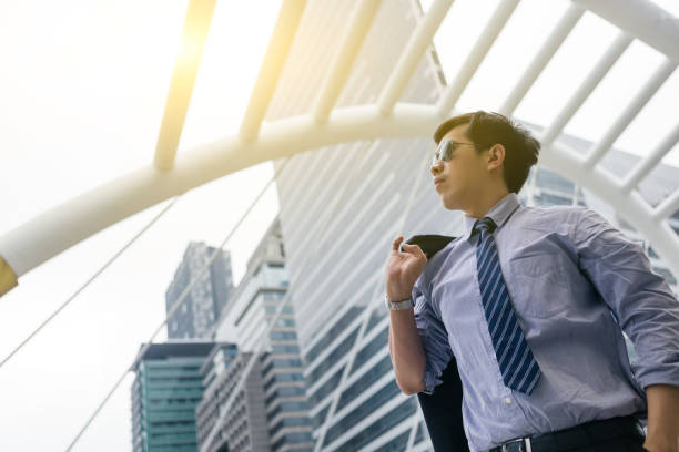 istock Asian businessman standing outdoors with office building in the background, low angle view 916944678