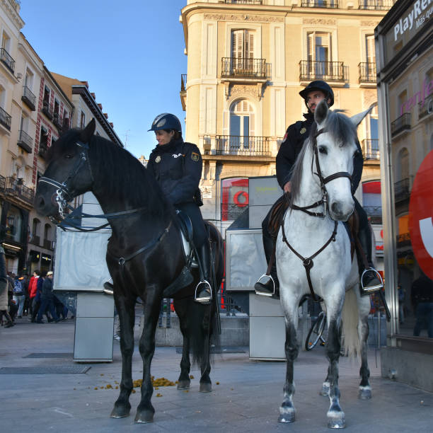 Police force in Madrid Madrid, Spain - January 31, 2018: Young people policewoman and policeman with black winter uniforms patrolling on horseback in the city centre of Madrid police policewoman women spain stock pictures, royalty-free photos & images