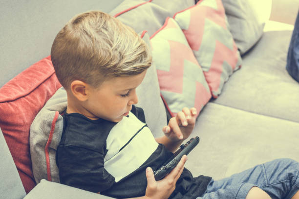 istock Little boy playing video games on the sofa. 916951918