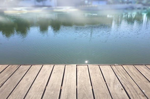 Empty rustic wooden table with defocused lake water and mist at background
