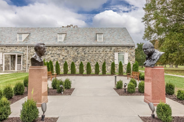 Franklin D. Roosevelt Presidential Library at Springwood Estate with Delano Roosevelt and Winston Churchill busts and Blue Sky with Clouds, Hyde Park, New York. The Franklin Delano Roosevelt Presidential Library and Museum with busts of president Delano Roosevelt and UK prime minister Winston Churchill (prime minister from 1940 to 1945 and again from 1951 to 1955). FDR was the 32nd President of the United States (1933–1945). The library is located on the grounds of Springwood, the Roosevelt family estate in Hyde Park, New York. Vivid blue sky with clouds and landscaped grass are in the image. Canon EOS 6D (full frame sensor). winston churchill prime minister stock pictures, royalty-free photos & images