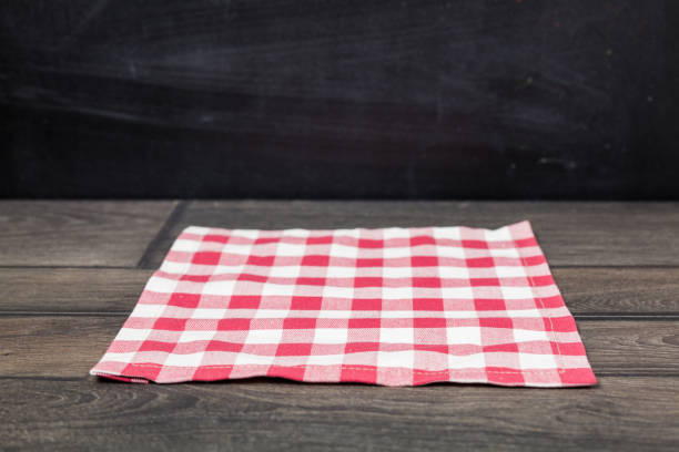 Red napkin  on dark wooden table. Copy space. Black wall background. Front view.